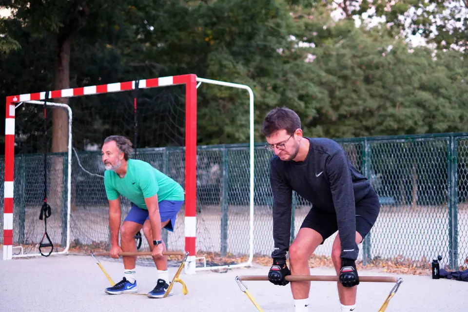 Senior et son partenaire d'entraînement en soulevé de terre avec bâton et élastiques