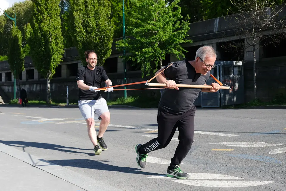Senior et son partenaire d'entraînement tirant ensemble sur un bâton relié à des élastiques, sur les quais